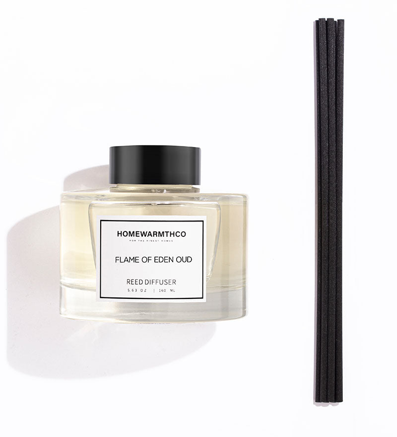 A luxury reed diffuser by HomeWarmthCo with black reeds in a clear glass bottle