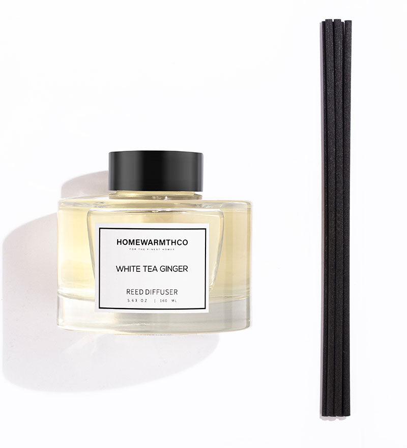 A luxury reed diffuser by HomeWarmthCo with black reeds in a clear bottle