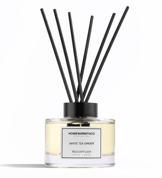 A luxury reed diffuser by HomeWarmthCo with black reeds in a clear bottle
