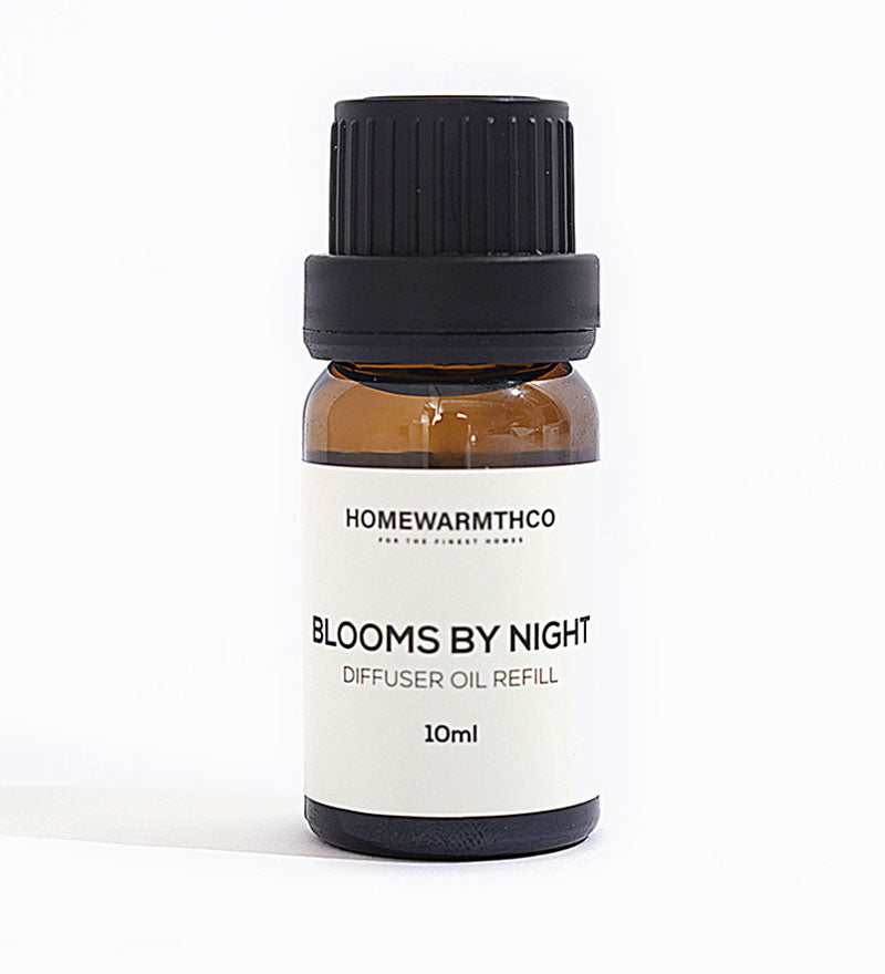 A 10ml bottle of 'Blooms by Night' diffuser oil with a black cap and white label, under natural lighting.