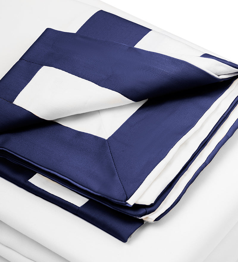 A set of navy and white patterned duvet covers displayed on a bed