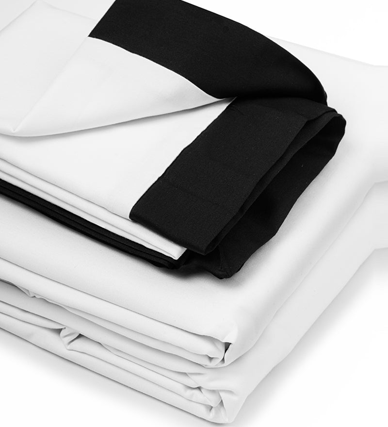 A bed with a white duvet cover and black-piped edges