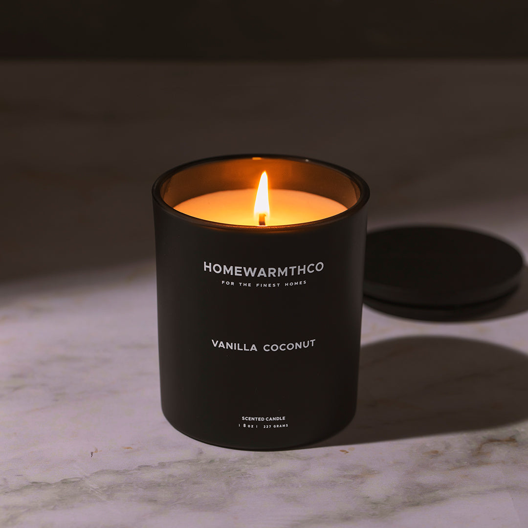 vanilla coconut scented candle in a black putted on a floor