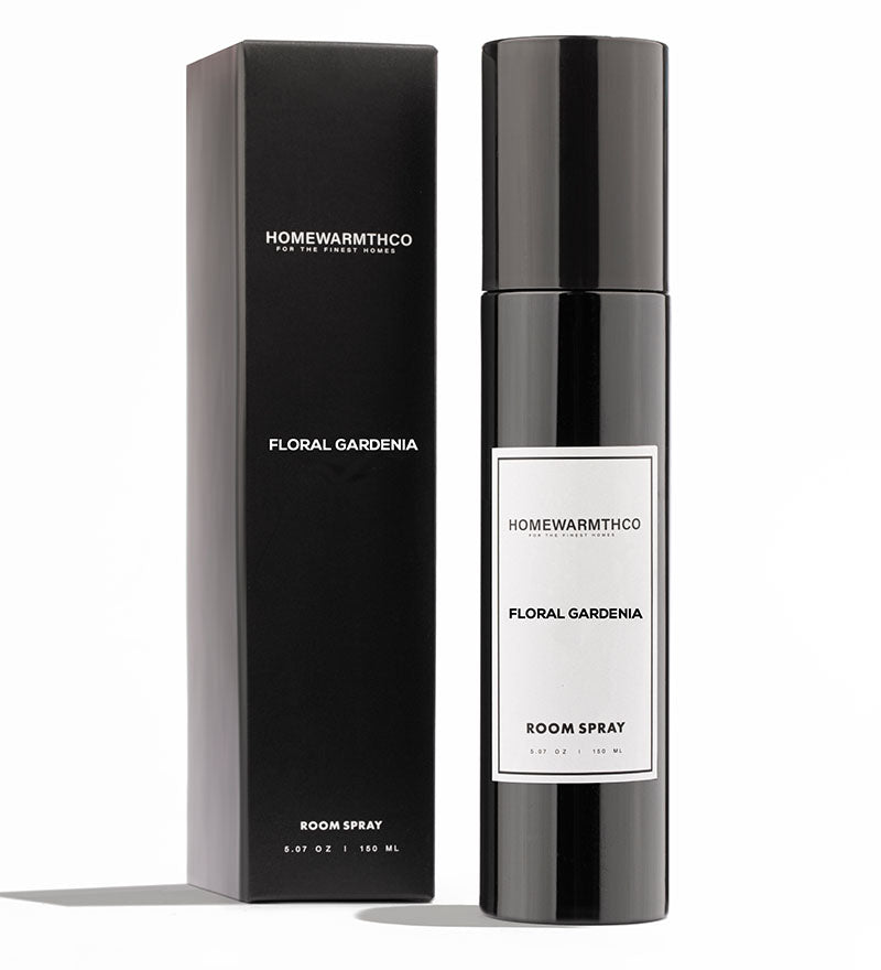 A black bottle of Floral Gardenia room spray with a white label, placed next to its black packaging box with the product name printed on it.