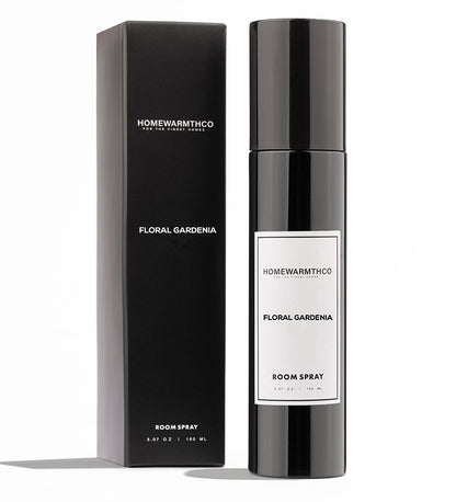 A black bottle of Floral Gardenia room spray with a white label, placed next to its black packaging box with the product name printed on it.