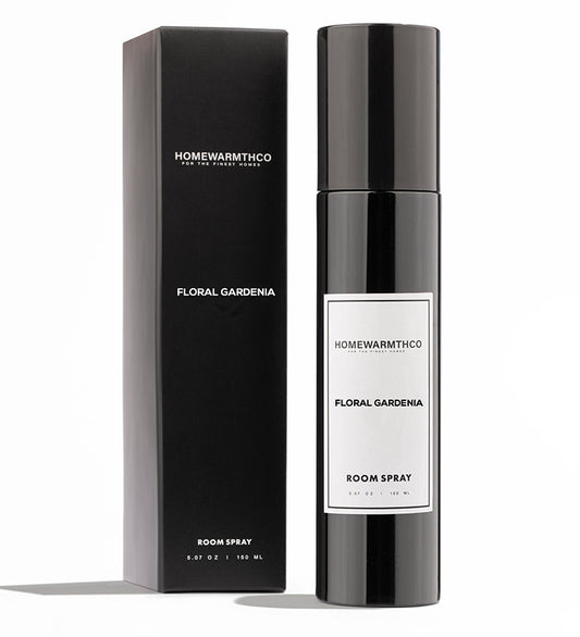 A black bottle of Floral Gardenia room spray with a white label, placed next to its black packaging box with the product name printed on it.