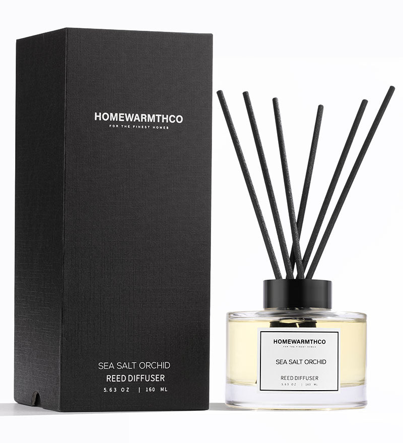 A luxury reed diffuser from HomeWarmthCo with black reeds in a clear bottle, labeled Sea Salt Orchid, with a black box packaging.