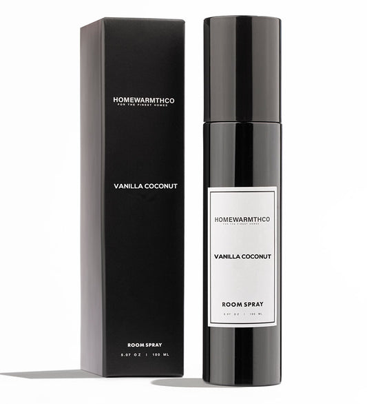 A black bottle of Vanilla Coconut room spray with a white label, placed next to its black box packaging with the product name and description.