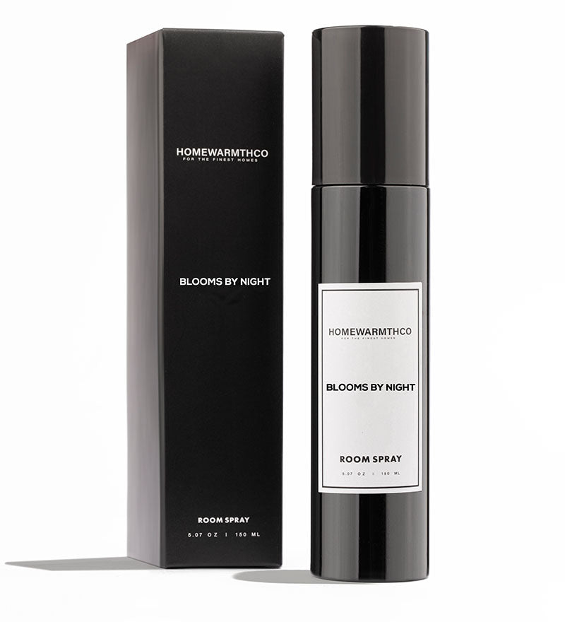 A black room spray bottle with white label text, placed next to its black box packaging, both labeled 'BLOOMS BY NIGHT ROOM SPRAY'.
