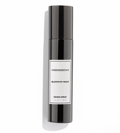 A black room spray bottle with white label text, placed next to its black box packaging
