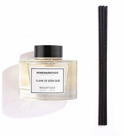 A luxury reed diffuser by HomeWarmthCo with black reeds in a clear glass bottle