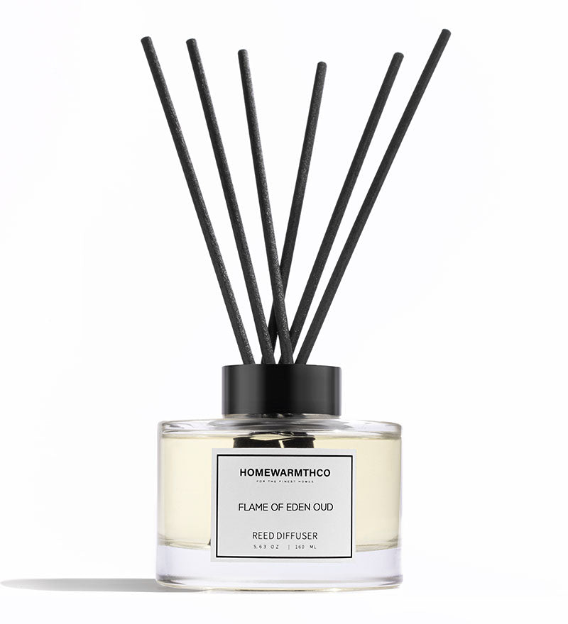 A luxury reed diffuser by HomeWarmthCo with black reeds in a clear glass bottle