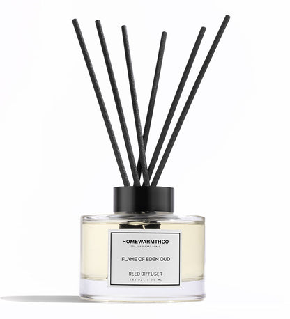 A luxury reed diffuser by HomeWarmthCo with black reeds in a clear glass bottle