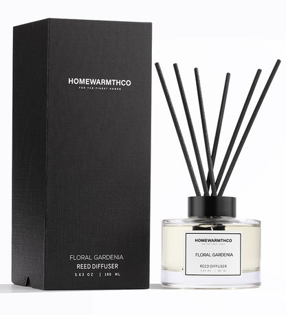 A luxury reed diffuser by HomeWarmthCo with floral gardenia fragrance, including a clear bottle with oil, black reeds, and a black box packaging.