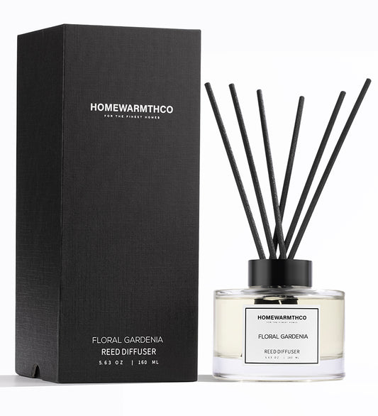 A luxury reed diffuser by HomeWarmthCo with floral gardenia fragrance, including a clear bottle with oil, black reeds, and a black box packaging.