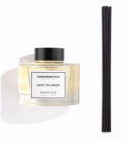 A luxury reed diffuser by HomeWarmthCo with black reeds in a clear bottle